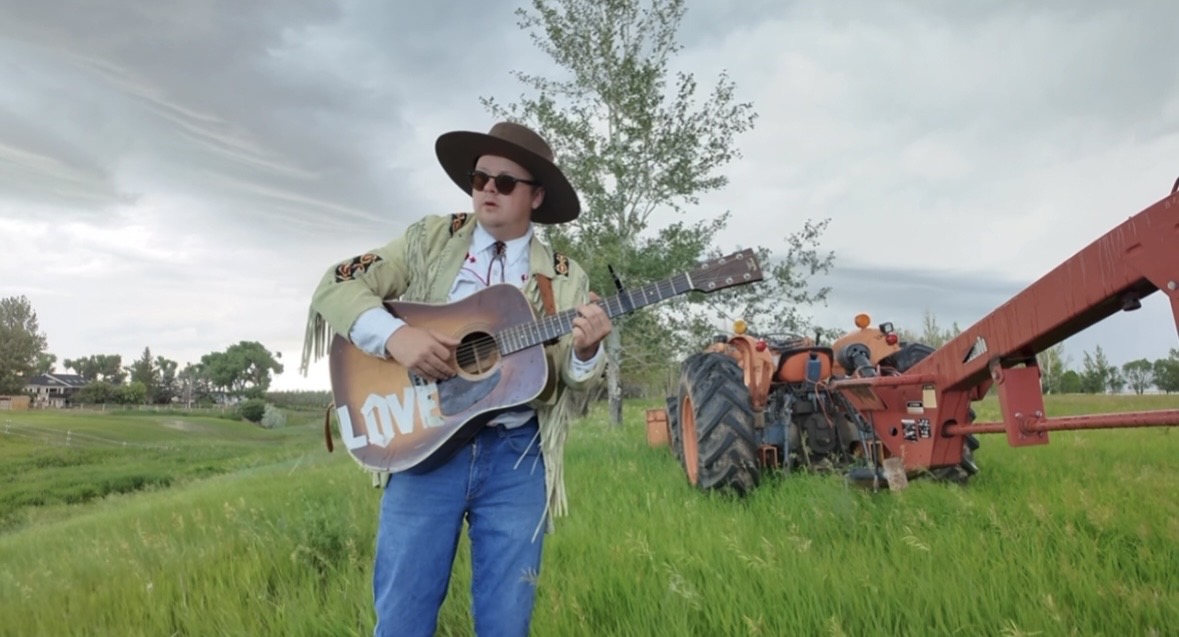 Joshua performing beside a tractor
